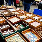 **Prompt:** A cluttered table at a Dutch "rommelmarkt" (flea market) overflowing with various board games. Some boxes are worn, others look new. People are browsing and examining the games. Emphasis on the "gezellig" (cozy, friendly) atmosphere. Some Euro coins are visible.